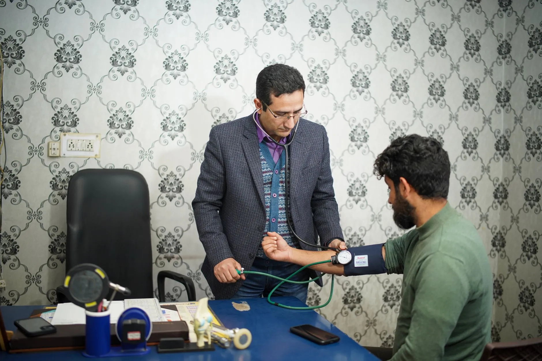 A doctor taking a patient's blood pressure during a consultation.