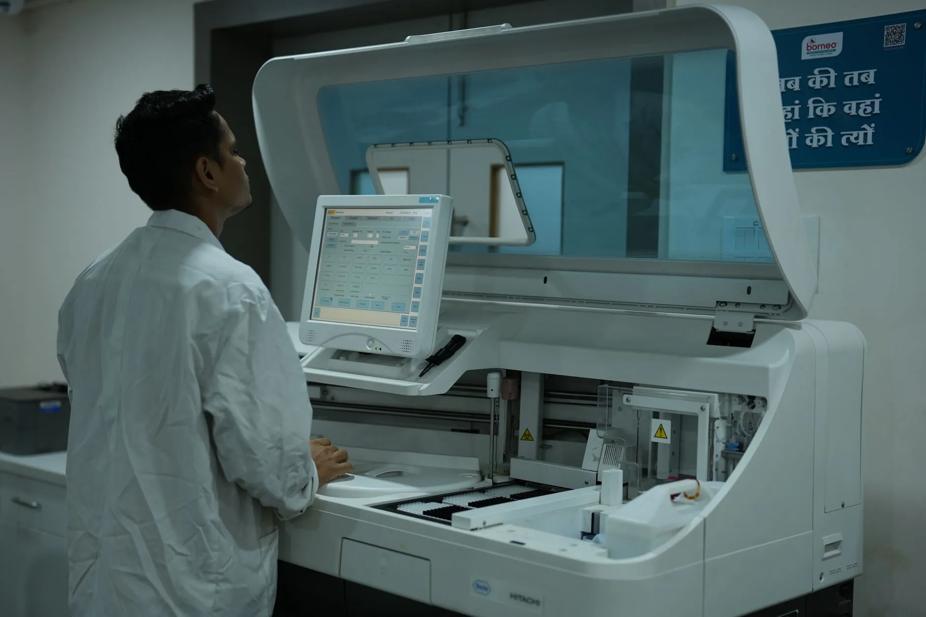 A technician operating a clinical analyser in a laboratory.
