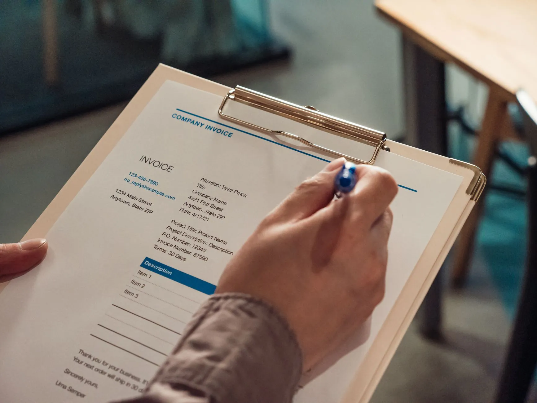 A hand holding an invoice on a clipboard.
