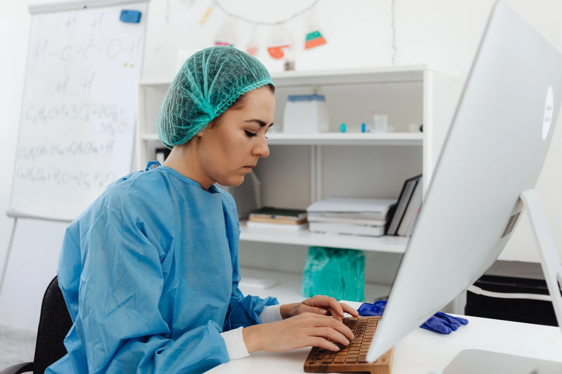 A healthcare worker typing at a computer in a clinic.