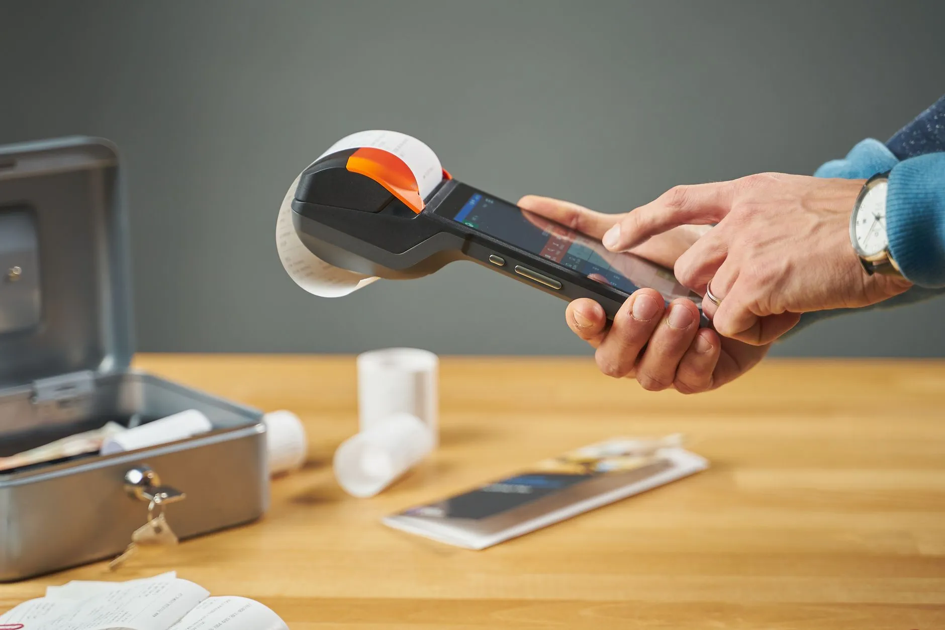 A hand operating a portable receipt printer.