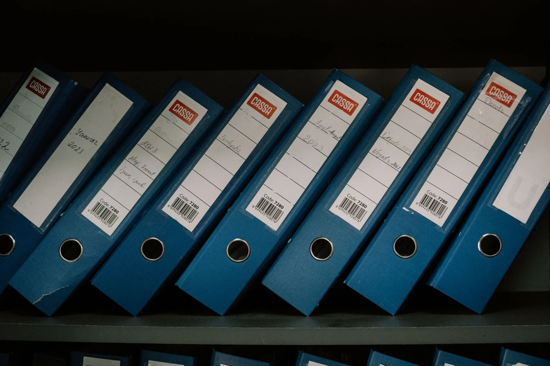 Labelled office binders arranged on a shelf.