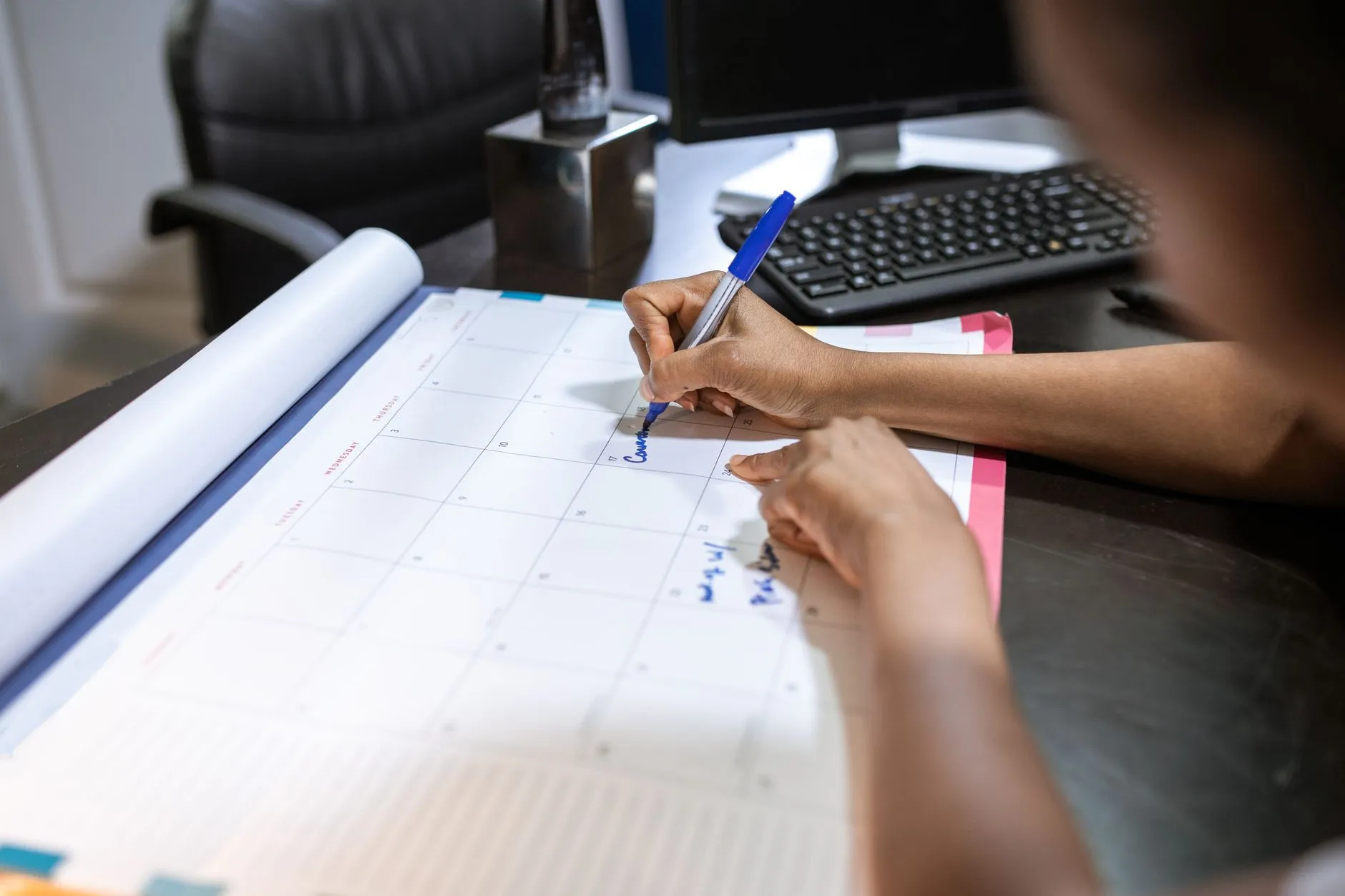 A person writing on a desk calendar.
