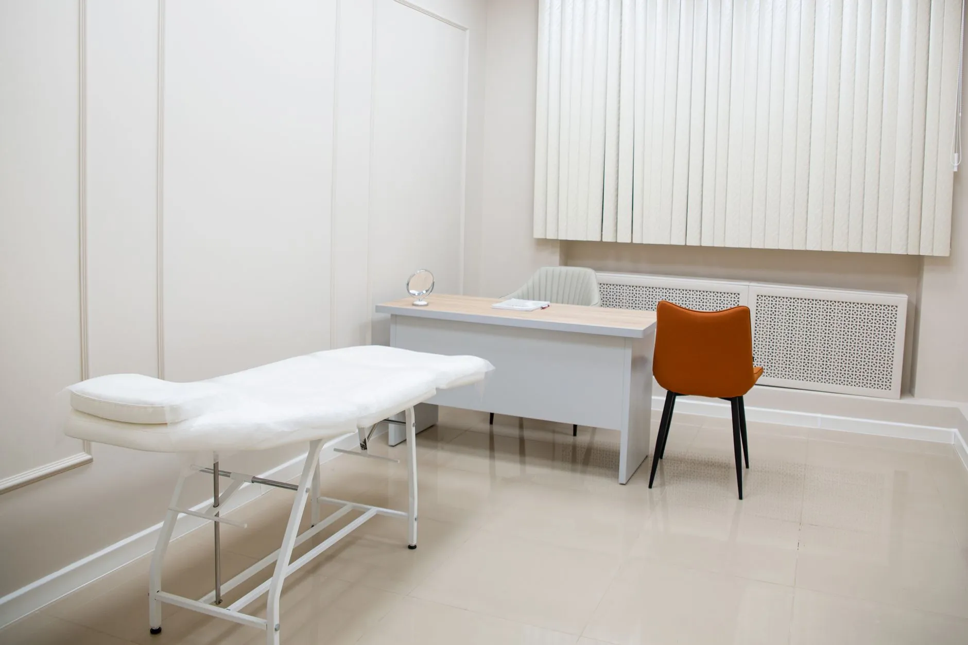 A newly fitted consulting room with an examination couch, desk and chairs.