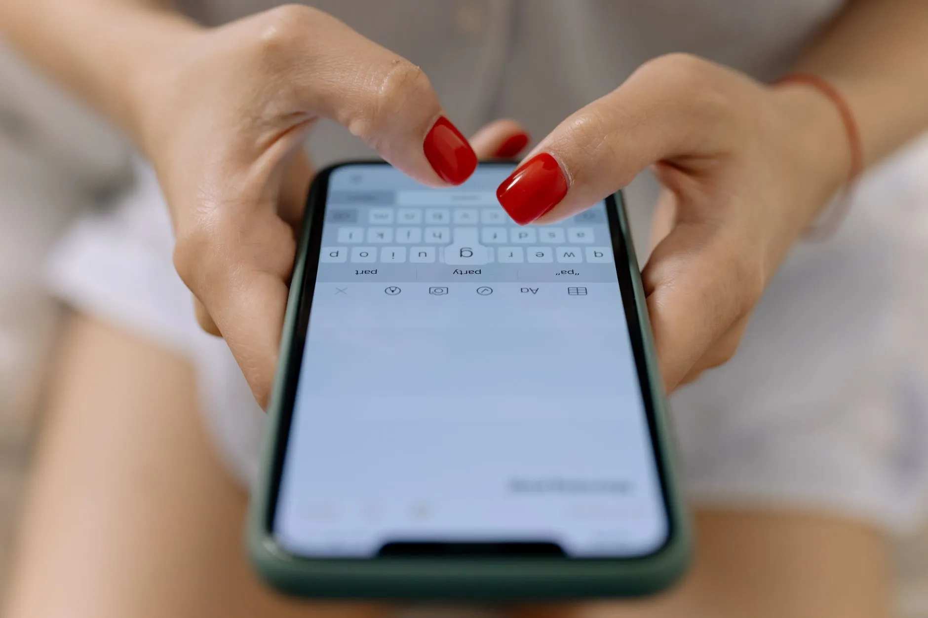 Hands typing a message on a smartphone.